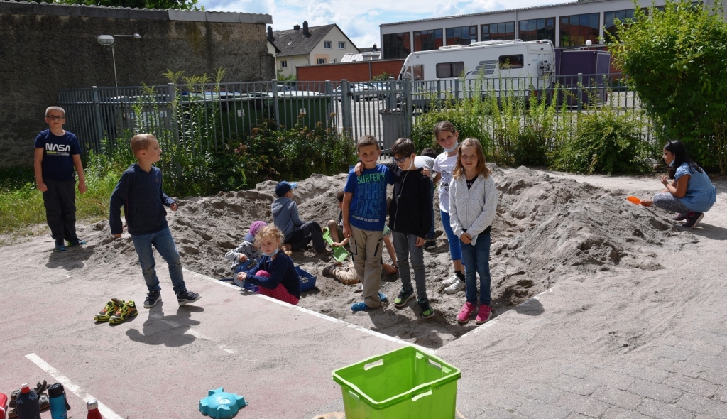Kinder der Ferienbetreuung spielen im Sand auf dem Gelände der FES.