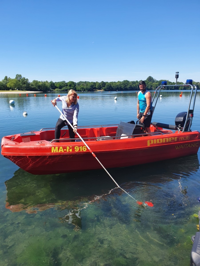 Hygienekontrolleurin Sarah-Vanessa Samuelsen mit Schwimmmeister Markus Hester bei der Entnahme einer Wasserprobe am Weinheimer Waidsee. (Foto: Landratsamt Rhein-Neckar-Kreis/Archivbild aus 2021) 