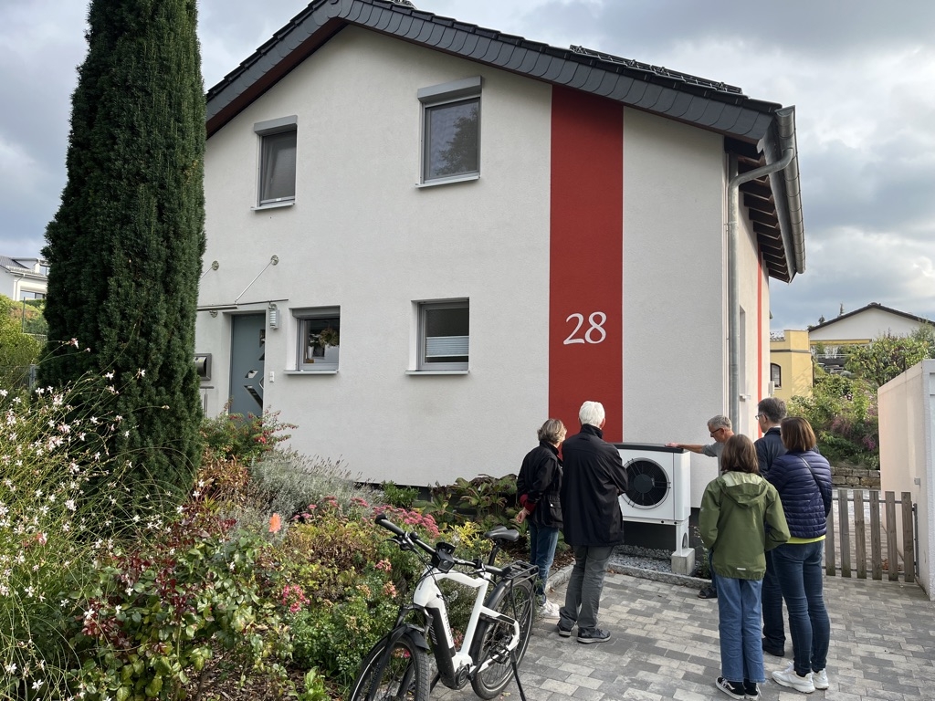 Menschen begutachten eine Wärmepumpe vor einem Wohnhaus. Bild: KliBA. 