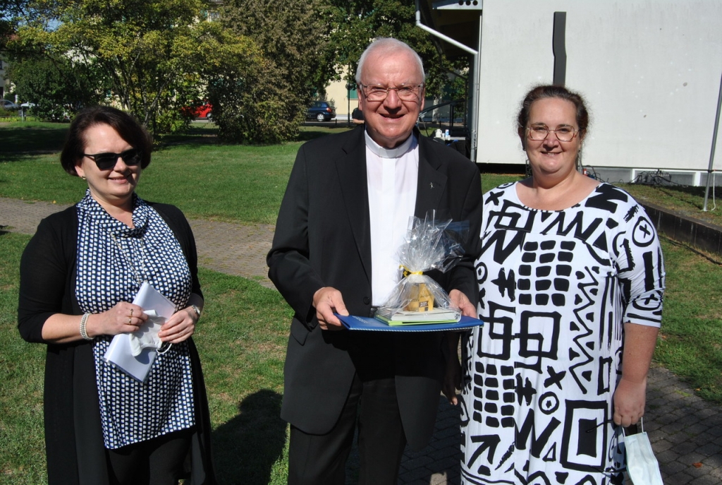 Marion Kolb und Carmen Kurz-Ketterer überreichen Pfarrer Wolfgang Gaber das Geschenk der kath. Kirchengemeinde.