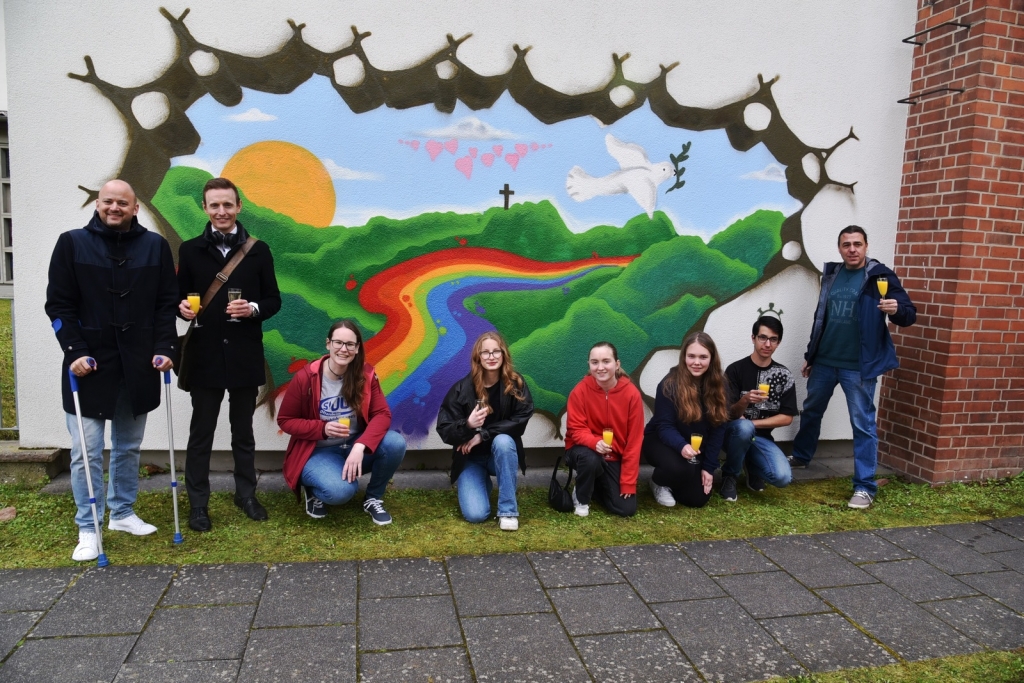 Das fertige Graffiti am Evangelischen Gemeindehaus. vlnr: Bürgermeister Pascal Seidel, Pfarrer Dr. Simon Layer, Eva Leibig vom JUZ, die jugendlichen Graffiti-Sprayer, Jugendreferent Sebastian Längerer